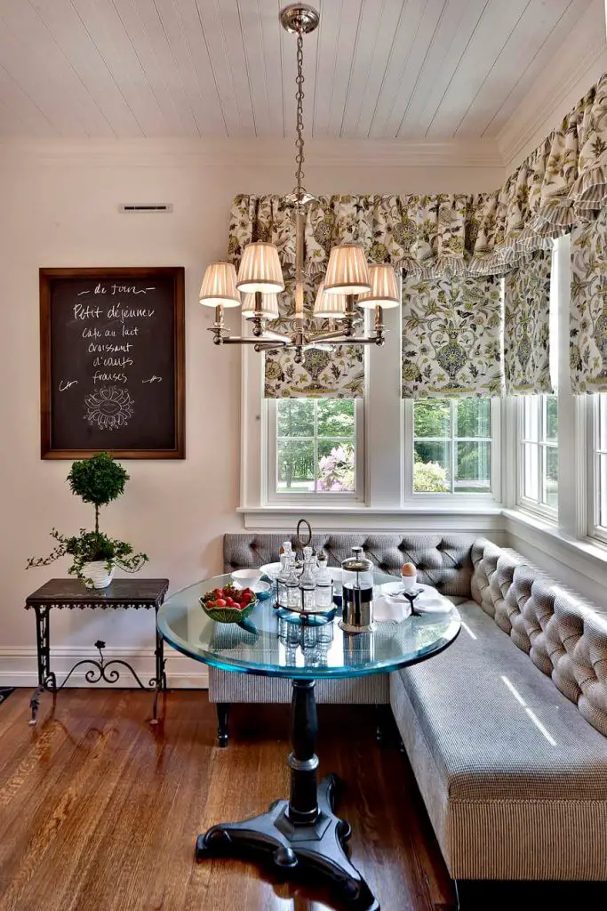 A tufted banquette and glass topped bistro table grace this traditional kitchen