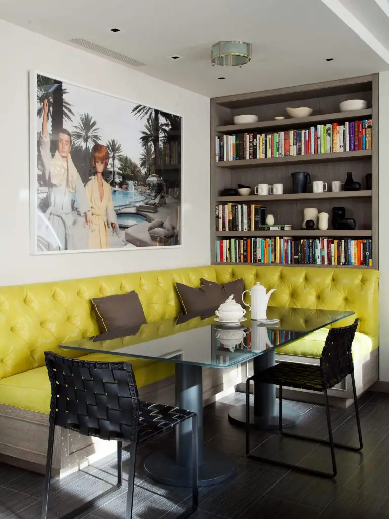 A tufted yellow leather banquette and Barbie doll inspired art make for an eclectic breakfast corner in New York