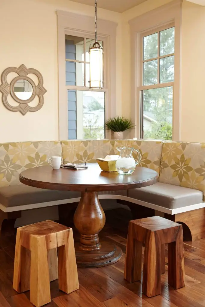 Chunky wood stools sit across from a round dining table and two toned breakfast banquette that create a stylish look for this Pentwater Lake, Michigan, kitchen