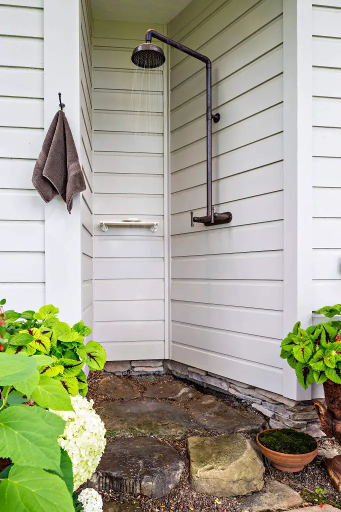 Outdoor shower is tucked into an alcove of a traditional home