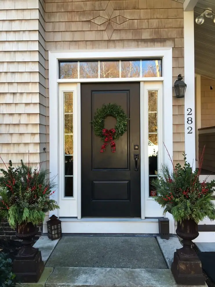 Plain boxwood with a plaid bow keep things sweet and simple, while urns festooned with branches, greens and berries amp up the entryway.