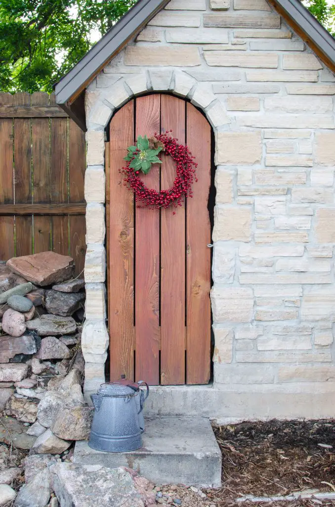 Red berries and a poinsettia flourish mark this potting shed’s simple plank door.