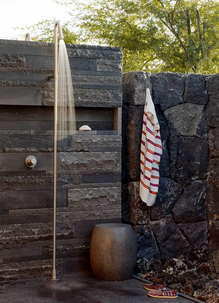 Shower wall complements the volcanic rock wall surrounding the Hawaiian property