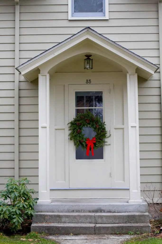 The center of the door is an unusual and pleasing placement for this wreath of classic fir and pine cones with a red bow.