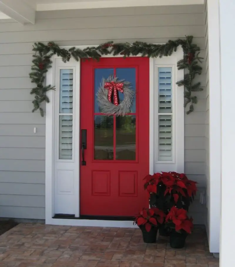 When your door is already cherry red, a wreath of twigs and a ribbon is a lovely choice. Poinsettias and a swag finish off the look.